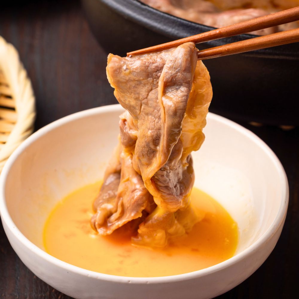 卵に絡めている 肩ロース すき焼きしゃぶしゃぶ肉